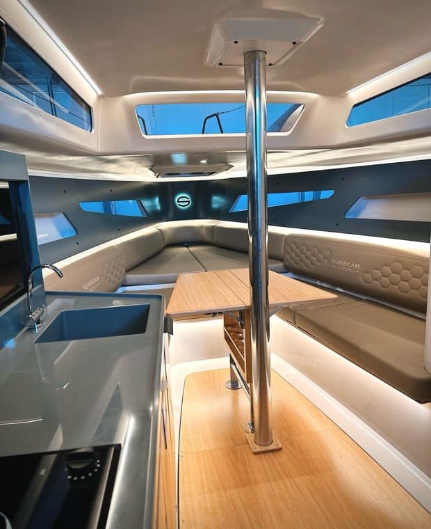 Innenraum der SUNBEAM 32.1 Yacht bei künstlichem Licht, mit einem Blick auf die voll ausgestattete Küchenzeile und die umgebenden Sitzbereiche.