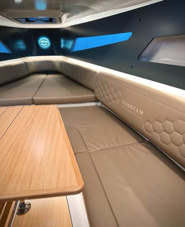 Komfortable Ecksitzgruppe im Inneren der SUNBEAM 32.1 Yacht mit Blick auf den eleganten Holztisch und das markante Innenraumdesign.