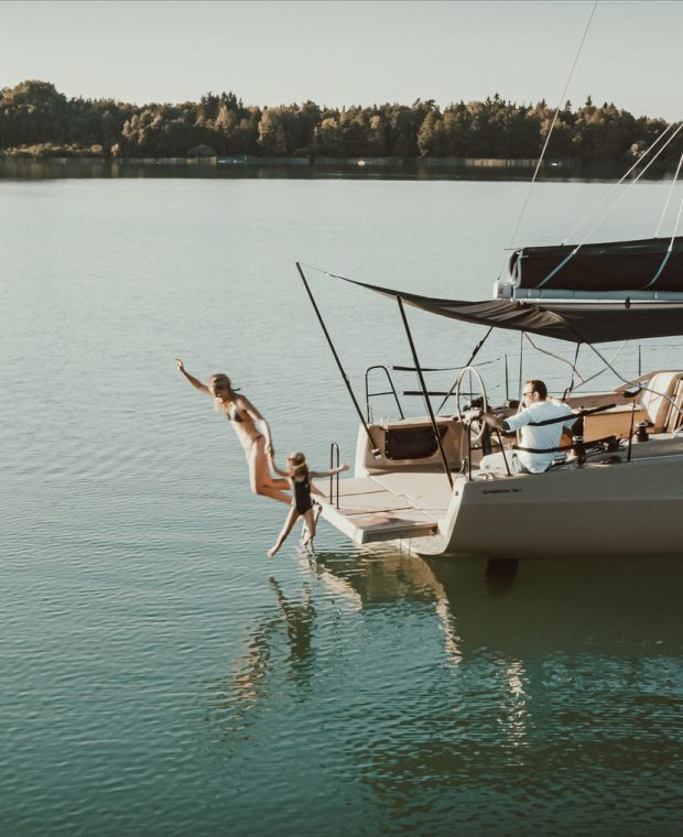 Freudiger Sprung ins Wasser von der Badeplattform einer Sunbeam Yacht, während Passagiere zuschauen