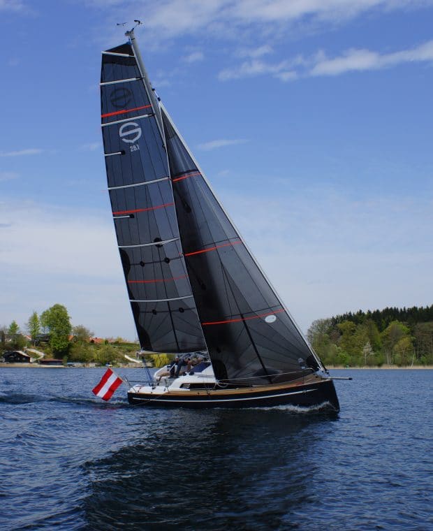 Eine Sunbeam 28.1 Yacht mit dunklen Segeln neigt sich bei leichter Krängung auf einem blauen See.