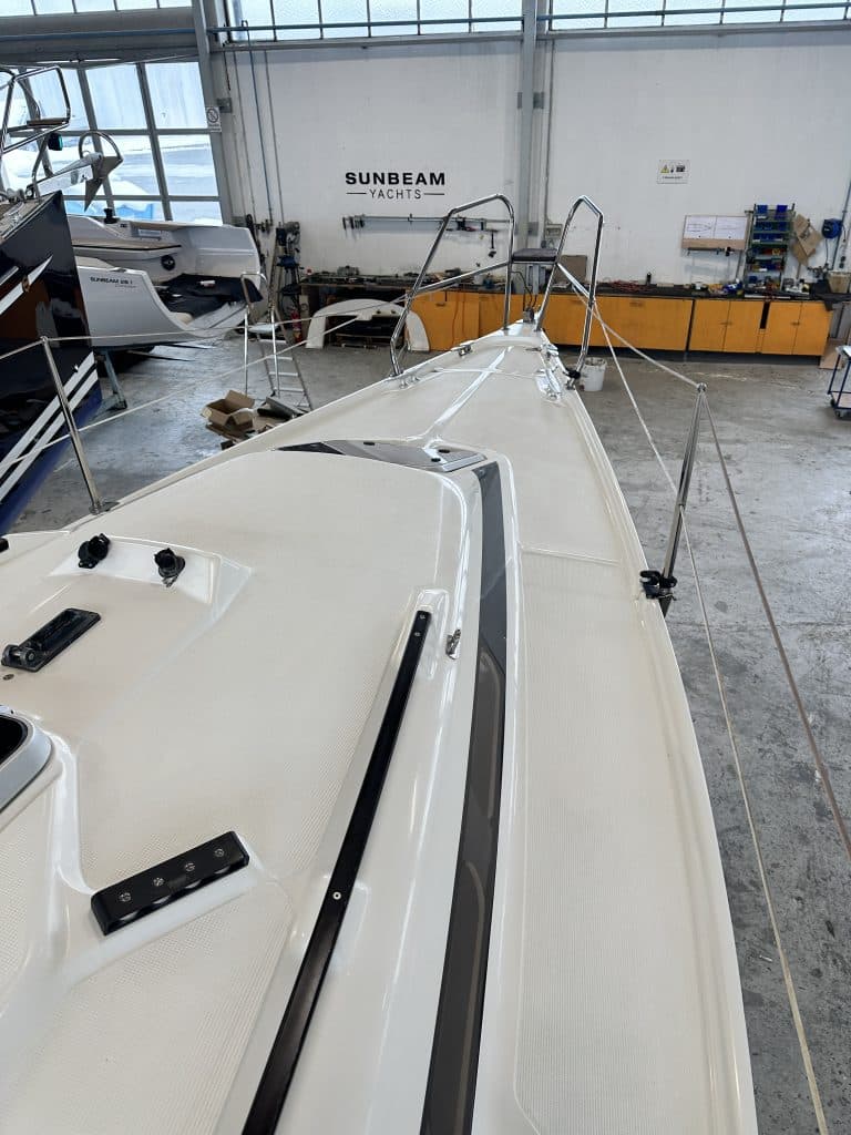 Deckansicht der SUNBEAM 29KS Yacht in einer Werkhalle mit Fokus auf das weiße Deck und Reling im Vordergrund.