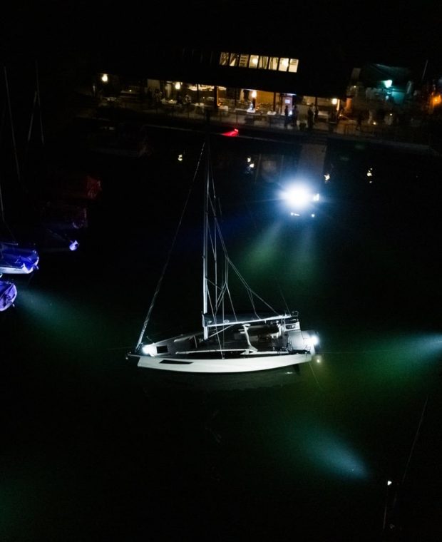 Eine Sunbeam Yacht beleuchtet von Unterwasserstrahlern in einer nächtlichen Szene in der Marina