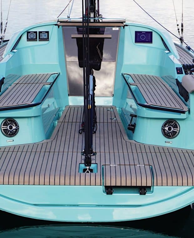 Rückansicht einer Sunbeam 29.1 Yacht, die im ruhigen Wasser ankert, mit einer auffälligen mintgrünen Rumpffarbe und symmetrisch angeordneten Holzbänken.