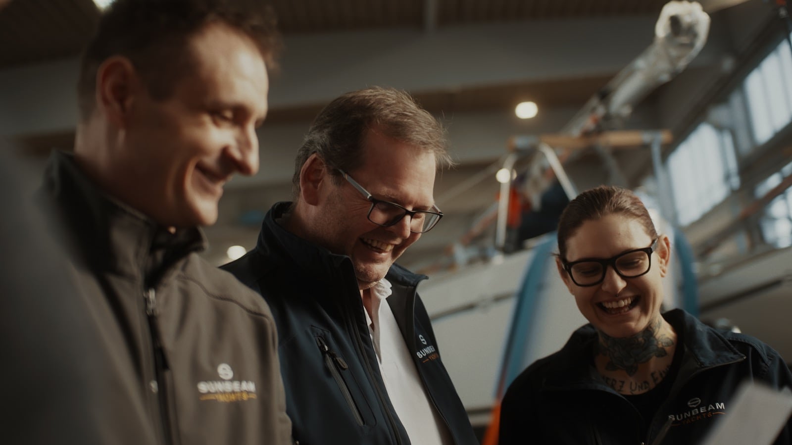 Drei fröhliche Sunbeam Yachts Mitarbeiter teilen einen leichten Moment in der Werft