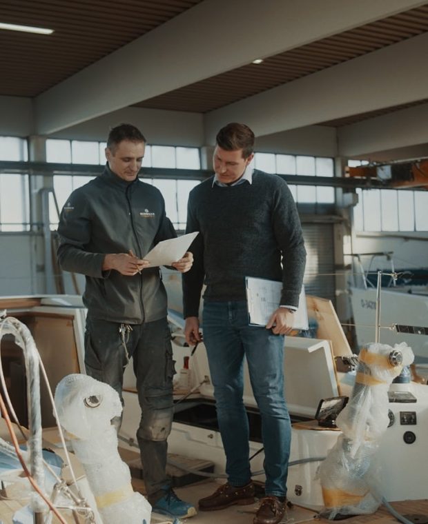 Zwei Sunbeam Yachts Mitarbeiter überprüfen Baupläne auf einer im Bau befindlichen Yacht